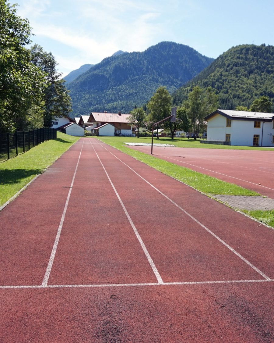 Empty school running track at golden hour, an anime-production key-art reference